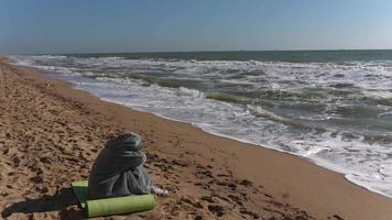 Person seated on a beach with head down video