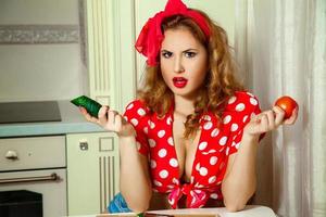 Portrait of beautiful woman in pinup tyle with cucumber and tomato in hands photo