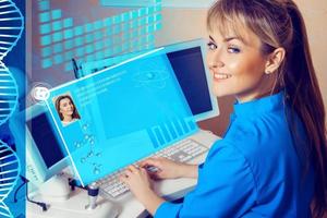 Female Doctor working in a cabinet at the computer and smiling photo