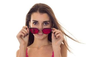 portrait of beauty young girl in pink light shirt looking at the camera and take off sunglasses isolated on white background photo