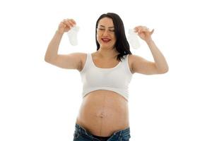 portrait of young funny pregnant woman with little socks in her hands isolated on white background photo