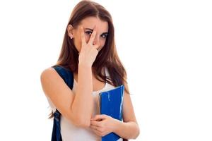 cheerful smart student girl in brown sport clothes with backpack on her shoulders and folder for notebooks in hands smiling and looking at the camera isolated on white background photo