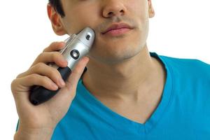 young guy shaves his beard shaving machines using close-up photo