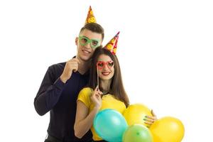 chico feliz con una chica con gafas de colores que lleva globos multicolores foto