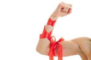 female hand with muscles wrapped with Red Ribbon close-up photo