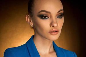 Beautiful young girl in blue jacket with beauty makeup in studio photo