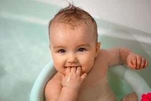 Cute newborn girl bathes in the bathroom photo