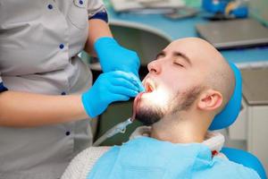 Photo of young adultmale patient takes a dental attendance in the dentist office