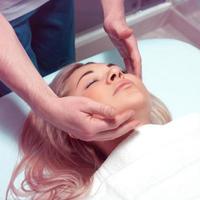 Square photo of Beautiful young woman receiving facial massage with closed eyes in a spa salon