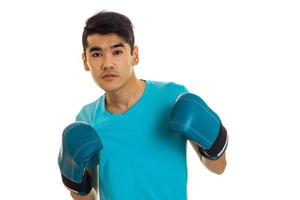 brunette sports man posing in blue boxing gloves in studio isolated on white background photo