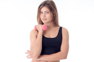 young girl in black top looks forward and keeps the dumbbell is isolated on a white background photo