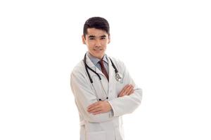 handsome elegant doctor in uniform with stethoscope with crossed hands smiling on camera isolated on white background photo