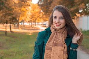 cute pin-up girl in a Brown scarf stands in the Park and smiles photo