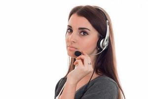 Portrait of serious young girl in headphones that corrects hand microphone is isolated on a white background photo