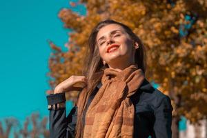 hermosa chica cerrando los ojos se para bajo el sol y sonríe foto