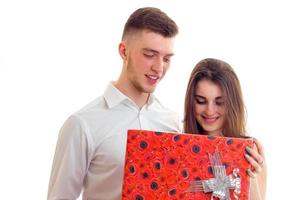 a young girl looks at the big red box on the gift that brought guy and smiling photo