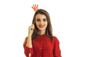 beautiful young girl in a red dress looks straight smiles and keeps near hair props in the form of the Crown photo