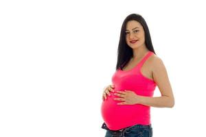 young pregnant brunette woman in pink shirt posing isolated on white background photo