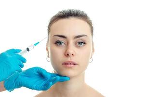 the doctor conducts injections in blue gloves on the face of a young girl have close-up photo