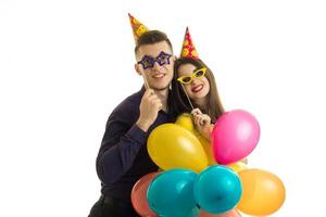 Una pareja joven y divertida posando en el estudio con globos en las manos y gafas foto