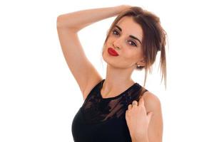 Portrait of an attractive young woman in a black dress and red lipstick that keeps hair and looks into the camera photo