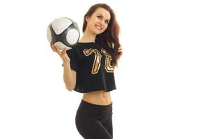 hermosa joven vestida de negro en la mano y se ríe de la pelota de fútbol foto