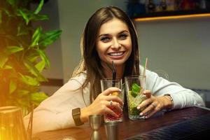 Happy young brunette  with two cocktails in hands photo