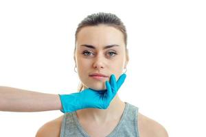 cosmetologist in a blue glove keeps the Chin from a young beautiful girl close-up photo