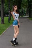 smiling girl shows hand gesture with two fingers and stands on rollers photo