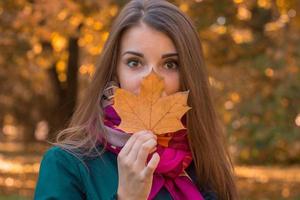 Portrait of a beautiful girl that keeps dry leaves near  person in the Park photo