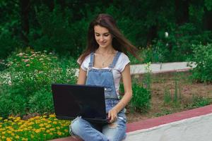 smiling beautiful lady sitting in a flower park on street prints on your laptop photo