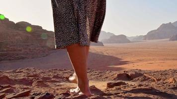 Schlanke schöne kaukasische Touristin steht barfuß auf einer Klippe, beobachtet den Sonnenaufgang und genießt den Urlaub im Wadi-Rum-Panorama am Beduinencampingplatz. beliebte Wadi-Rum-Wüste in Jordanien video