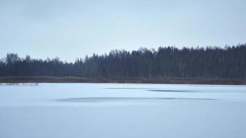 beau panorama de lac gelé avec des pas de pêcheurs sur un lac glacé avec une nouvelle glace fragile. dangers sur la glace et la pêche blanche. pêcheur video