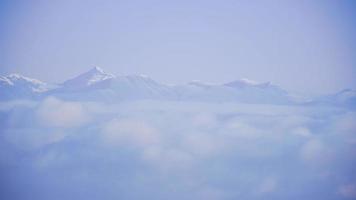 montagne enneigée avec brume et nuages forment des couches sous les sommets enneigés. panorama des montagnes touchéti video