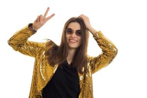 chica glamurosa divertida con gafas y una chaqueta brillante muestra un gesto de mano y una sonrisa foto