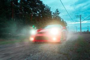 Red car moves over rough terrain with headlights photo