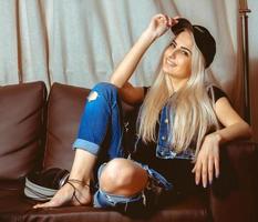 Square portrait of beauty blonde woman in casual clothes sits on couch photo