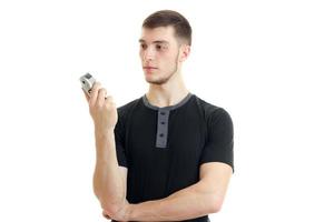 tall young strong guy stands up straight and holding a Clipper to shave photo
