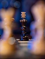 Chess board with chess pieces on blue background. Concept of business ideas and competition and strategy ideas. Black king and figures close up. photo