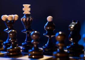 Chess board with chess pieces on blue background. Concept of business ideas and competition and strategy ideas. Black king and figures close up. photo