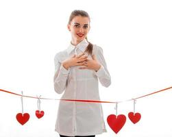 young girl in white clothes standing near ribbons with hearts photo