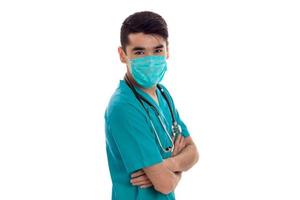 a young doctor with stethoscope and the mask on the face looks at camera photo