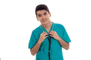 portrait of handsome young brunette male doctor in uniform with stethoscope posing isolated on white background photo