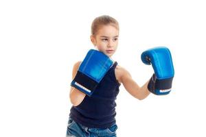 la niña parada frente a la cámara con grandes guantes de boxeo está aislada en un fondo blanco foto