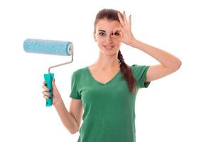 a young girl in a green t-shirt holding a roller to paint walls isolated on white background photo