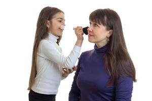 little girl makes a makeup to her mother photo