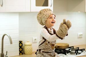retrato de una linda niñita casera en una cocina blanca. foto