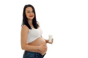 bella mujer embarazada posando con un vaso de leche aislado de fondo blanco foto