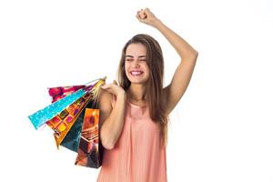 happy girl keeps a lot of large packages and lifted her arm up isolated on white background photo