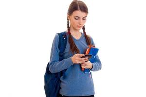 sad smart student girl with backpack on her shoulders and folder for notebooks in her hands looking down isolated on white background photo